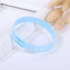 Light blue silicone wristband with the word ARGENT on it, placed next to some light-colored, oval objects.