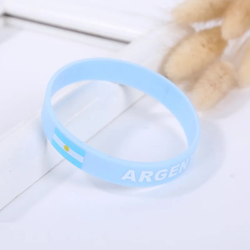 Light blue silicone wristband with the word ARGENT on it, placed next to some light-colored, oval objects.