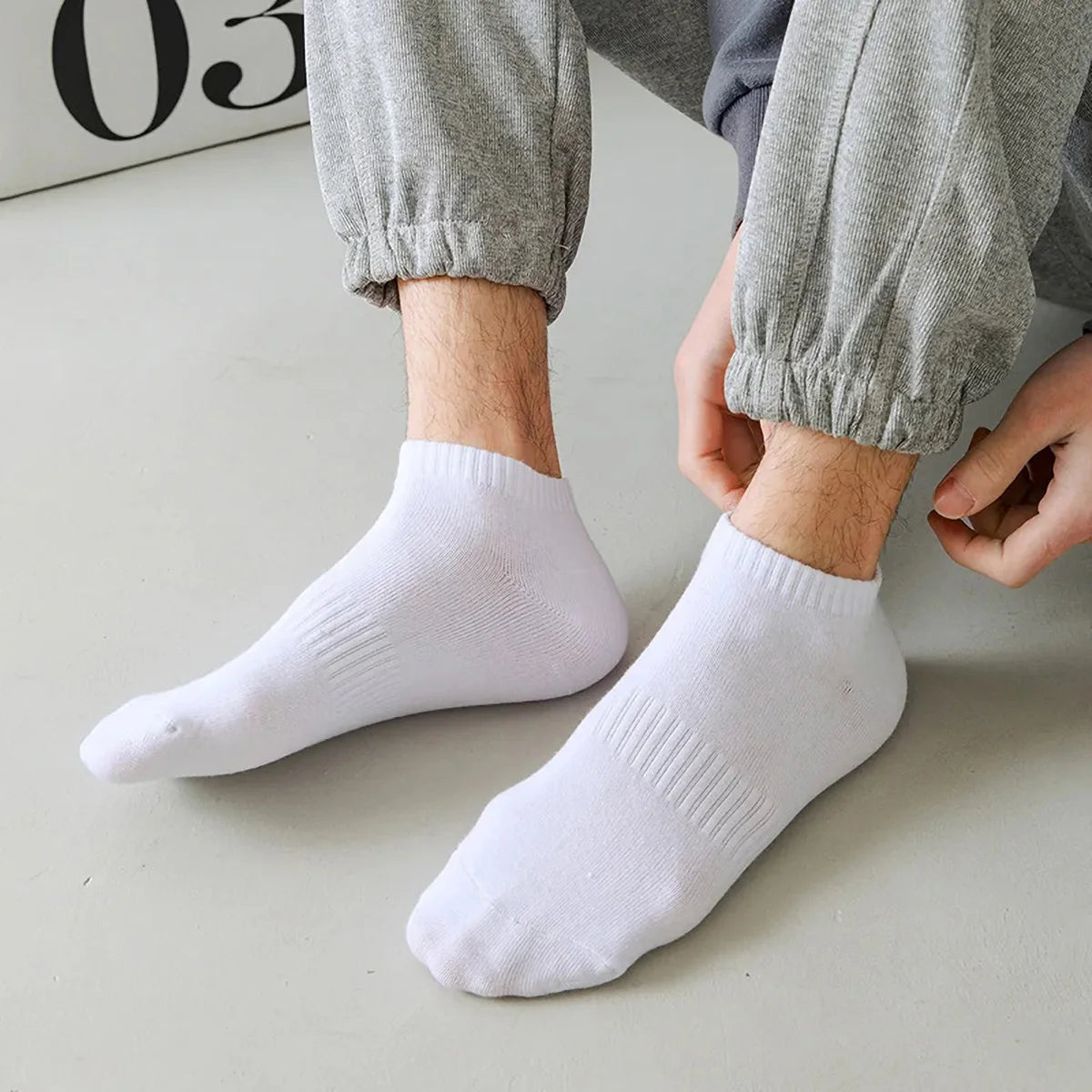 A pair of white thin ankle socks worn by a person, shown on their feet.