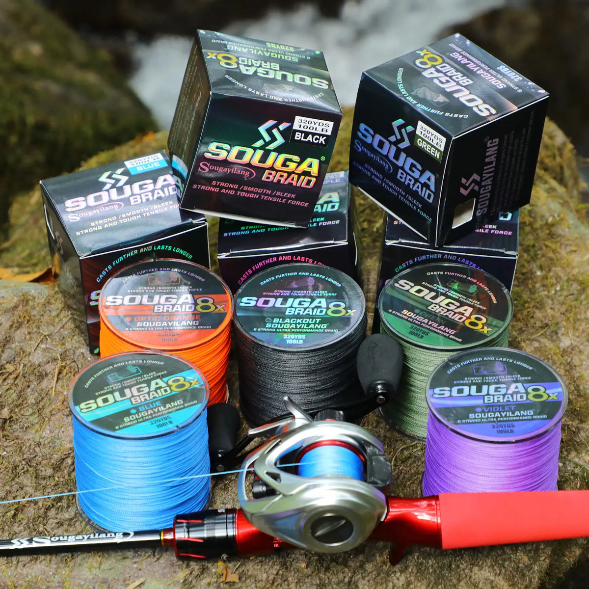 A collection of SOUGA BRAID fishing line spools and a fishing rod are displayed on a rock.