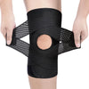 A black adjustable knee brace with compression support is being held on a person's leg.