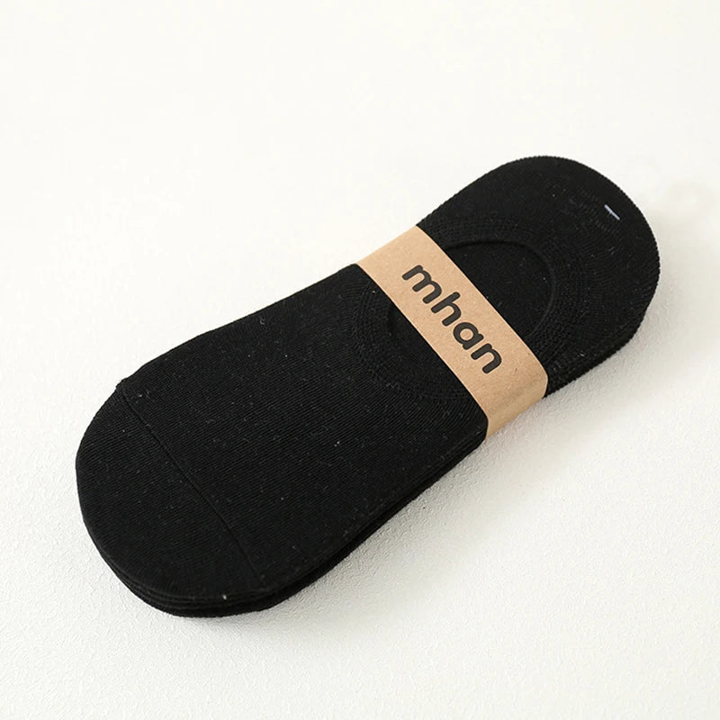 A black ankle sock with a light brown woven label displaying the name mhan.
