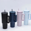 Un set de quatre grandes tasses isothermes en acier inoxydable noir, bleu foncé, rose et bleu clair avec pailles.