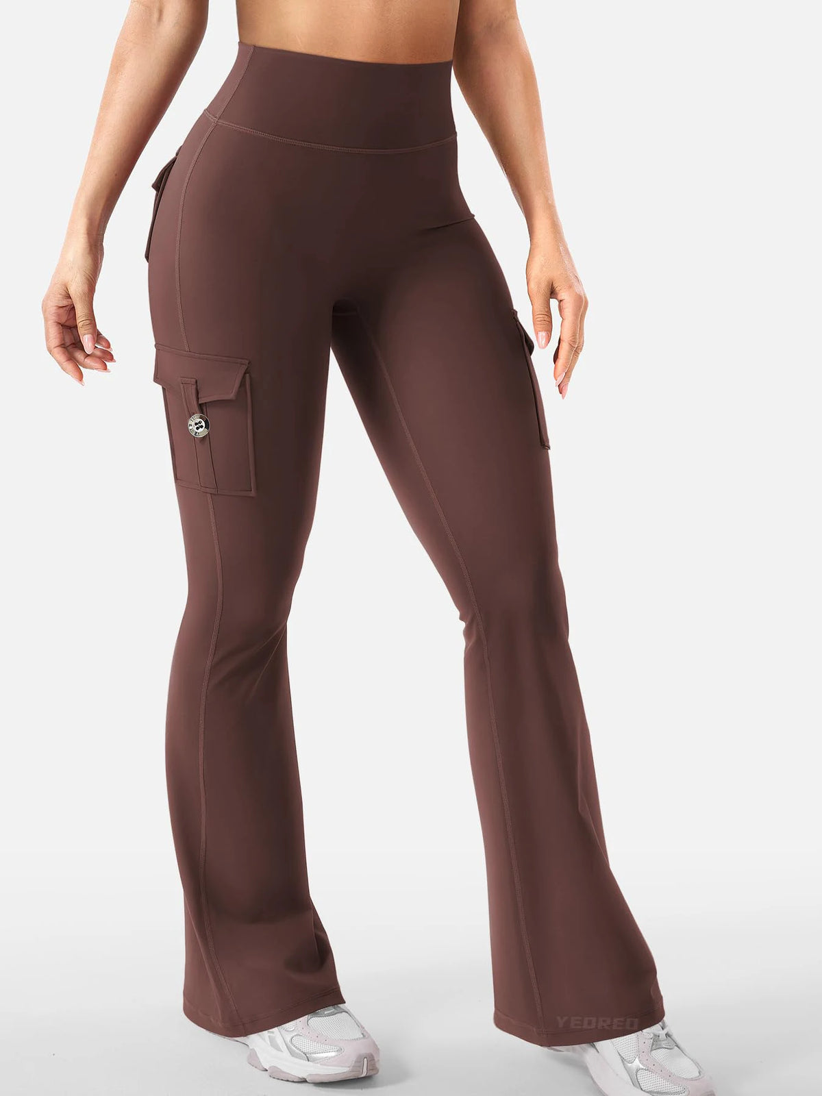 A model wears high-waisted brown flared fitness pants with side pockets.