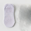 Une paire de chaussettes de yoga et de sport blanches respirantes posées sur une surface claire.