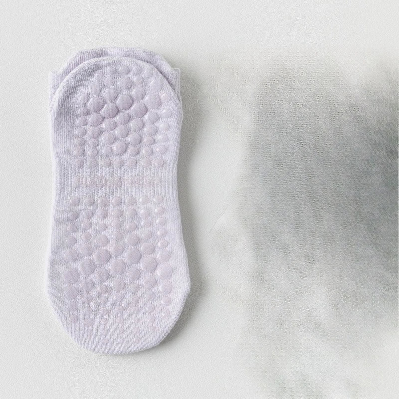 Une paire de chaussettes de yoga et de sport blanches respirantes posées sur une surface claire.