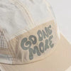 A close-up of a beige baseball cap with light gray text that reads GO ONE MORE