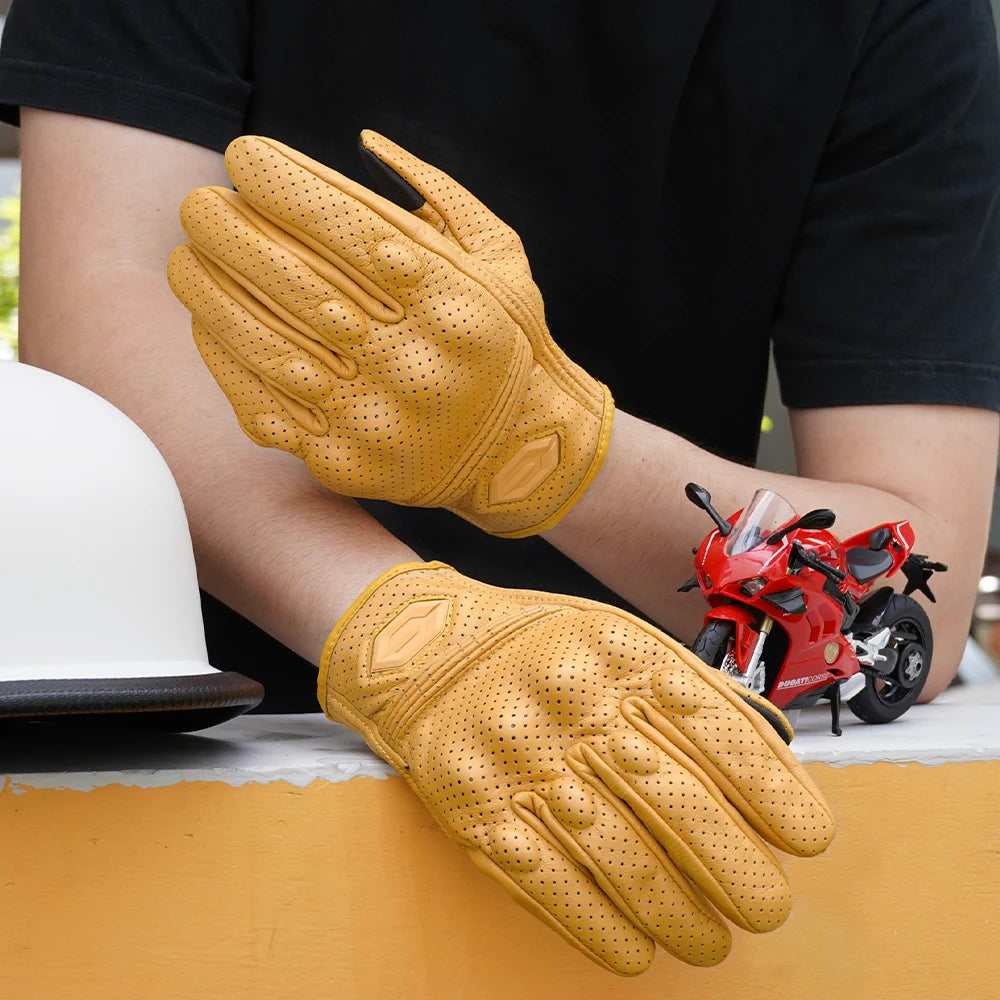 A pair of tan vintage leather motorcycle riding gloves are shown on a person's hand against a black shirt.