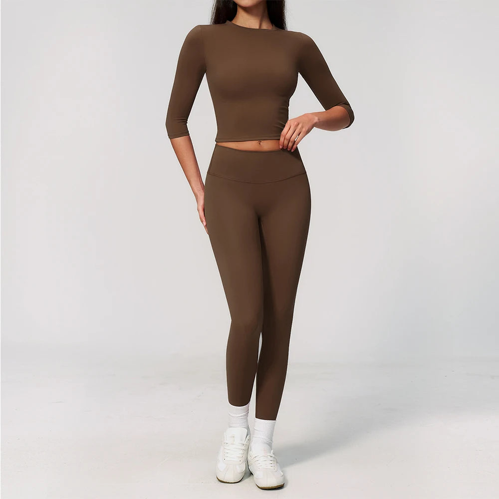 A woman wearing a matching brown long-sleeved top and leggings set for yoga and fitness.
