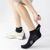 A close-up of a person wearing black breathable running socks with white accents and a light gray athletic shoe.