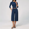 A woman wearing a navy blue yoga and fitness leggings set consisting of a long-sleeved top and high-waisted pants.