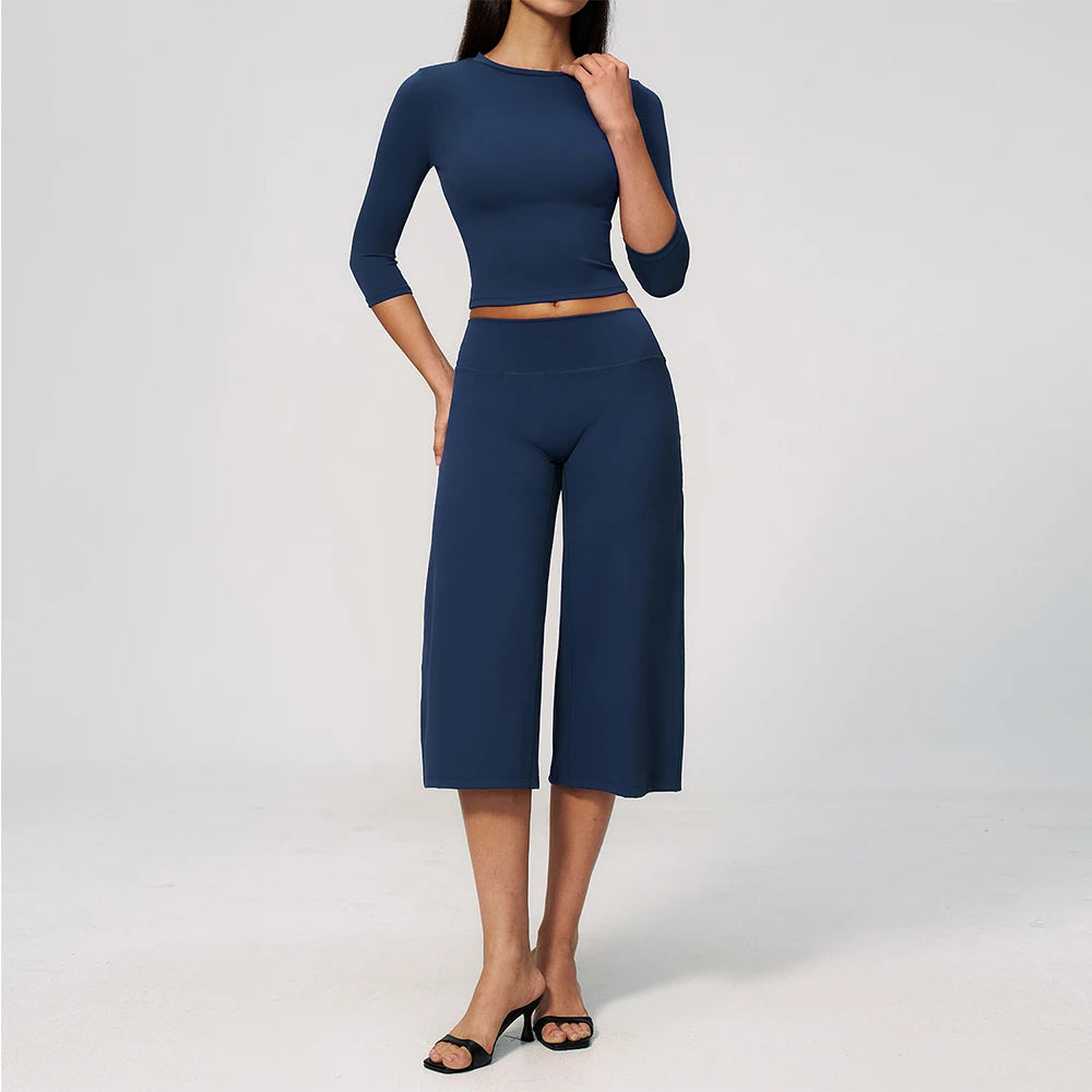 A woman wearing a navy blue yoga and fitness leggings set consisting of a long-sleeved top and high-waisted pants.