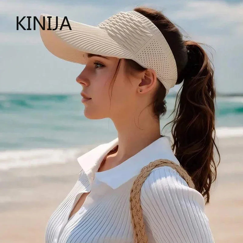 A woman wearing a white breathable anti-UV adjustable sun hat and a white top stands near the ocean.