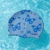 A silicone swimming cap with a blue butterfly print floating in clear water.