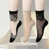 A set of sheer invisible lace socks in black and beige, displayed on a white surface.