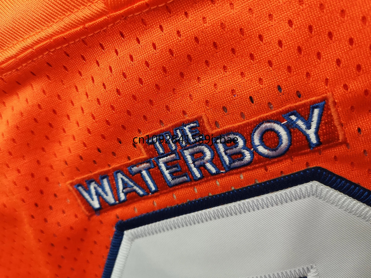 Nahaufnahme eines orangefarbenen Fußballtrikots mit blauem gesticktem Text, der 'THE WATERBOY' lautet