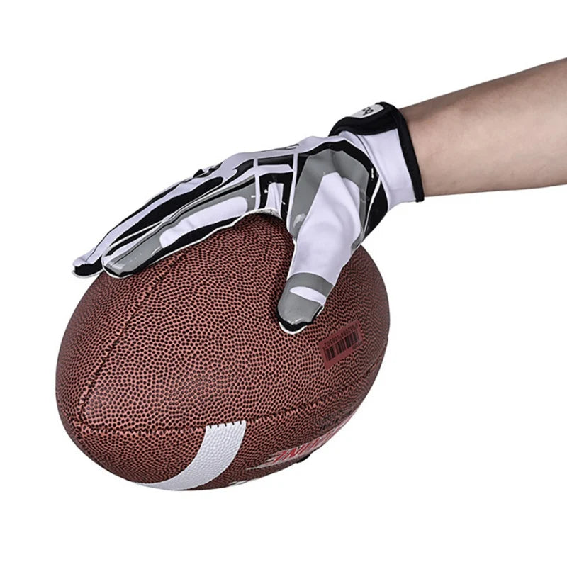 Une main portant des gants de sport anti-dérapants noirs et blancs de style rugby agrippant un ballon de rugby marron.