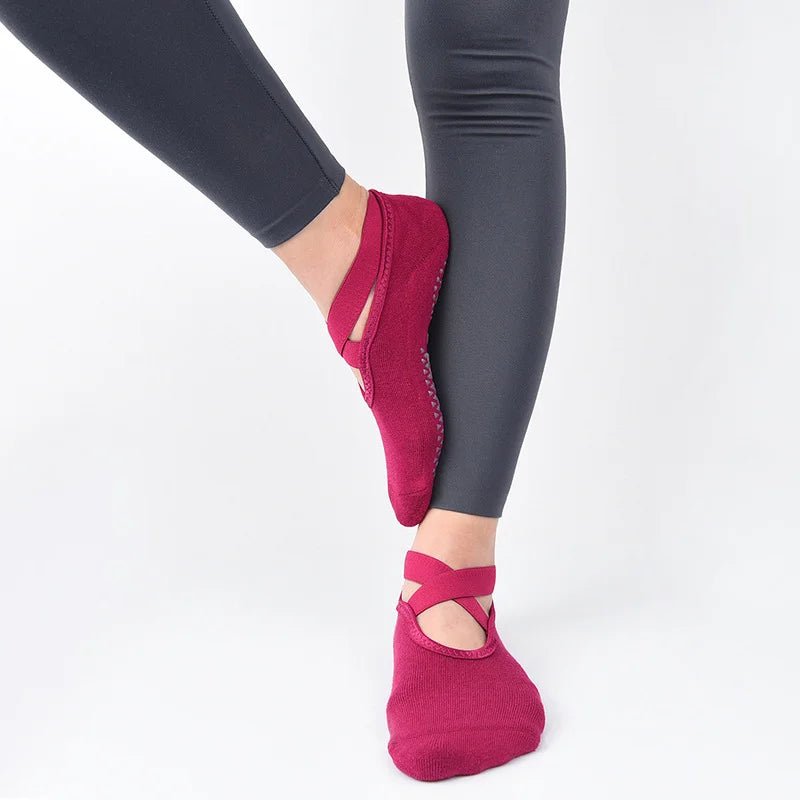 Un par de calcetines antideslizantes de color magenta intenso puestos en un pie, mostrados contra un fondo blanco.