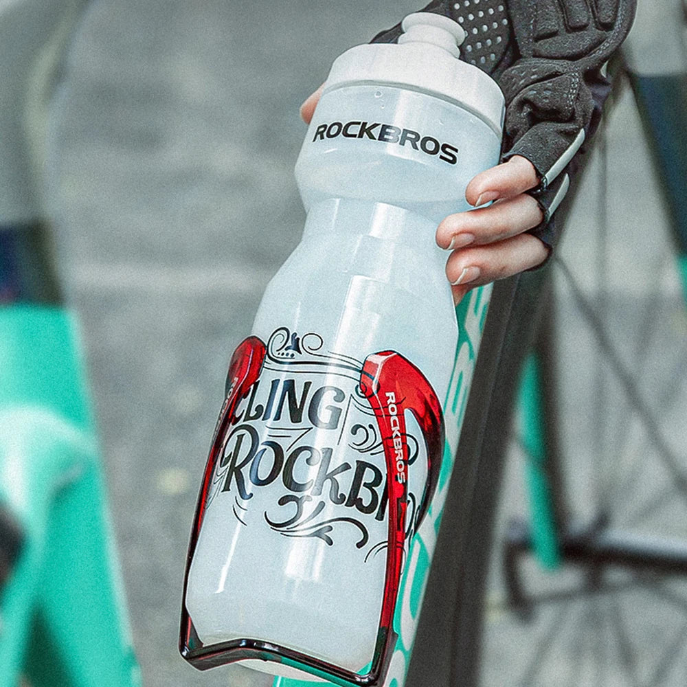 A hand holds a clear plastic sports water bottle with the Rockbros logo, featuring red accents.