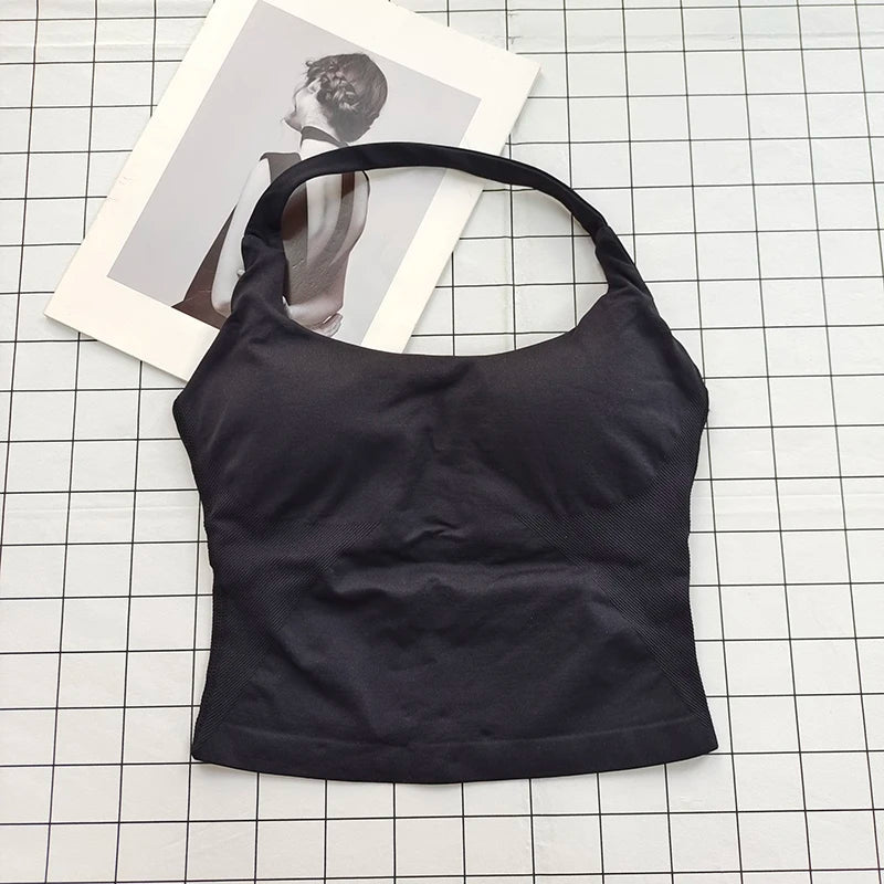 Black seamless sports camisole top laid on a white grid with a photo in the background.