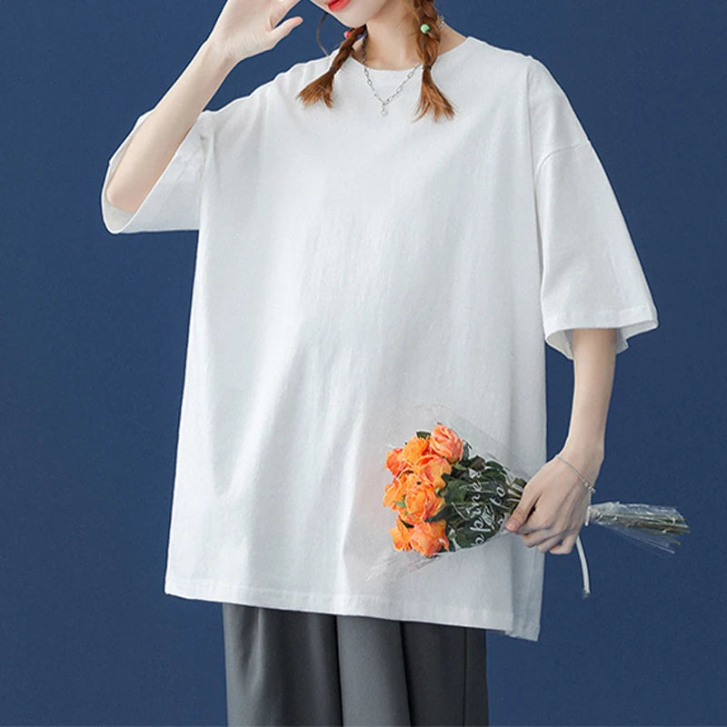 Eine Frau in einem weißen, oversized Baumwoll-T-Shirt hält einen Strauß orange-grüner Blumen.