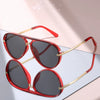Red-framed aviator sunglasses with gold accents resting on a light pink surface.