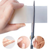 A hand holds a clear hydrocolloid wound care patch next to a surgical blade and several patches for skin healing.