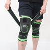 A person is holding adjustable sports knee pads, featuring black and neon green straps and padding, on their leg.