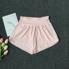 Light pink women's high-waist yoga and fitness shorts laid flat on a dark gray surface.