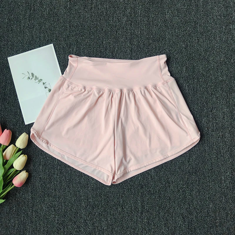 Light pink women's high-waist yoga and fitness shorts laid flat on a dark gray surface.