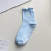 Light blue yoga socks with a scalloped cuff, a heart embroidery, and dotted detailing.