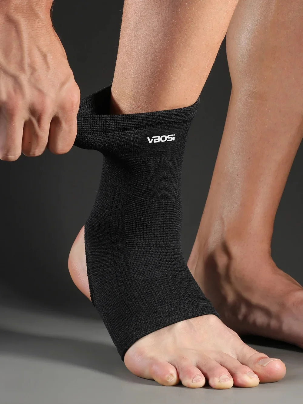 A person's ankle is shown wearing a black Breathable Ankle Support Brace for Injury Recovery.
