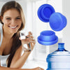 A woman is holding a glass and several blue reusable silicone water bottle lids in a bright indoor setting.