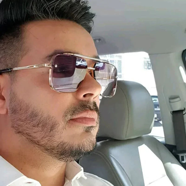 A man wearing classic square metal sunglasses indoors.