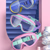 Three pairs of colorful swimming goggles are displayed against a pink background.
