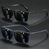 A pair of black vintage square sunglasses with dark lenses and a black frame resting on a dark surface.