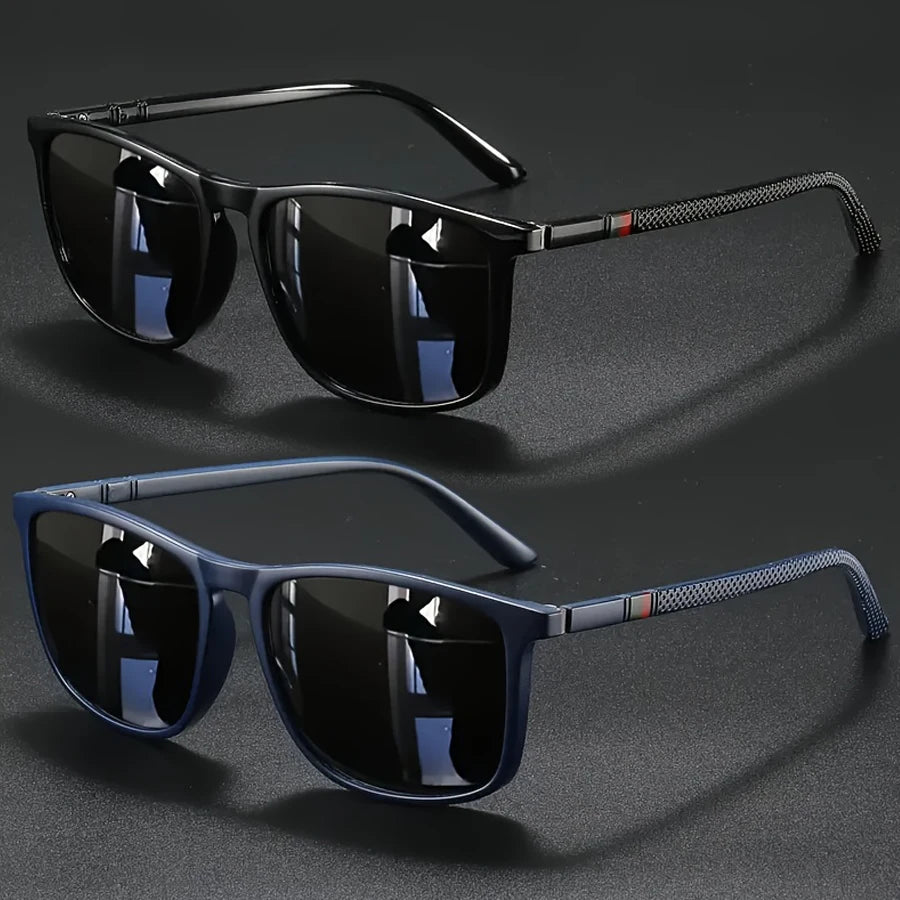 A pair of black vintage square sunglasses with dark lenses and a black frame resting on a dark surface.