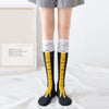 Paire de chaussettes noires montantes avec des pieds de poulet dessinés jaunes et une bordure blanche