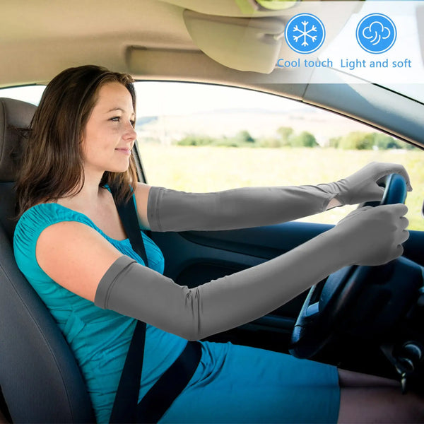 A woman wearing blue clothing is driving a car with UV protection elastic sun sleeves on her hands.