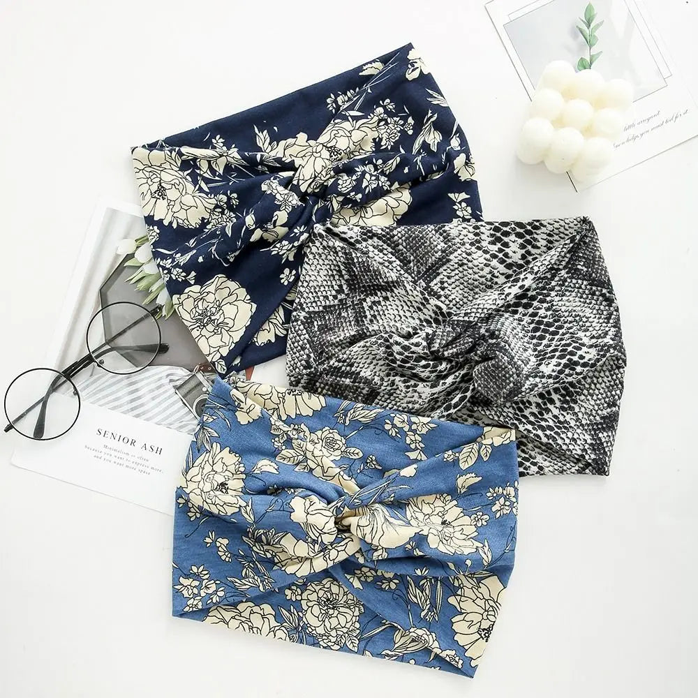 Three fabric headbands in navy floral, black patterned, and blue floral designs are displayed on a white background.