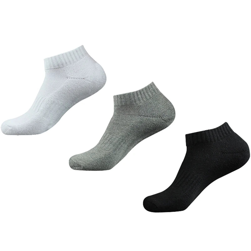Un paquete de tres calcetines deportivos de algodón para el tobillo en blanco, gris y negro.