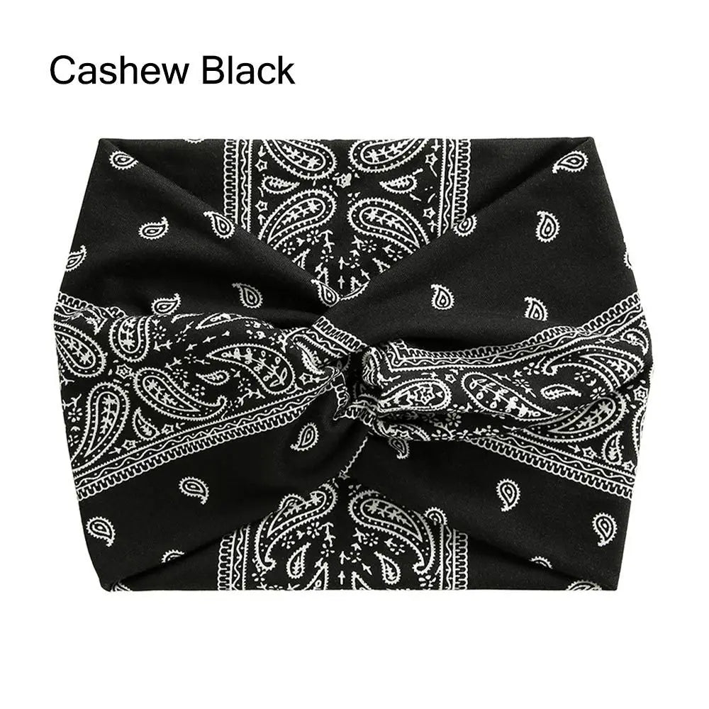 Black fabric headband with white paisley pattern, cross-knotted for yoga and workout.