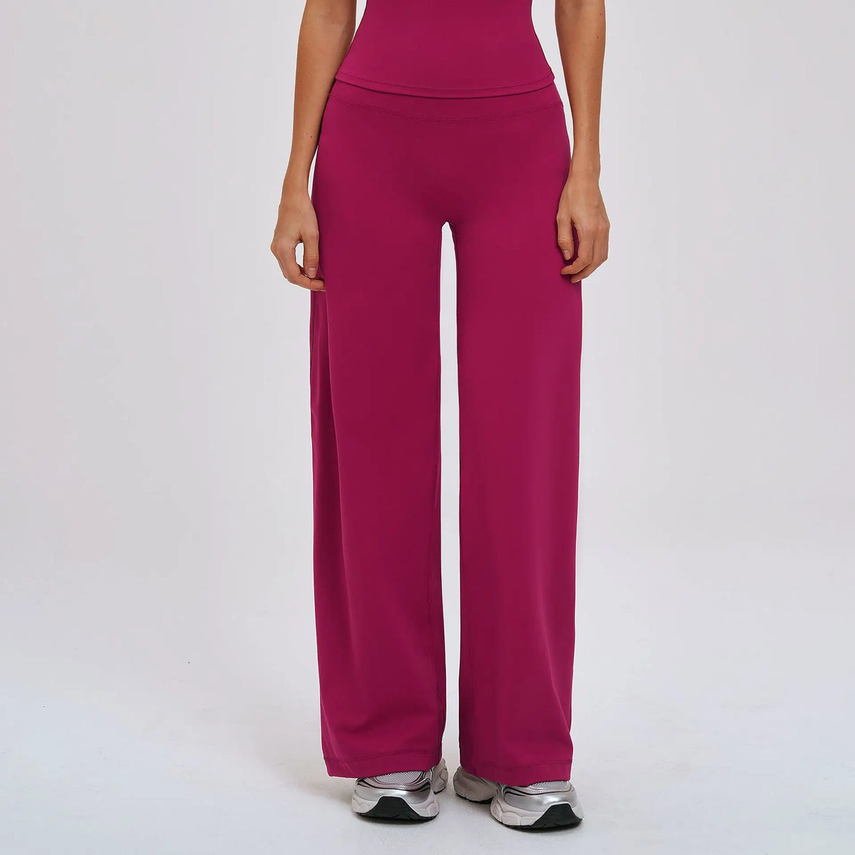 A person is wearing a solid magenta high-waist wide-leg yoga legging and gray athletic shoes.