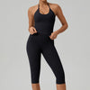 Eine Frau trägt ein schwarzes zwei-teiliges Yoga-Activewear-Set mit Tanktop und Leggings.