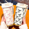 A hand holds a white and pink patterned double-wall insulated stainless steel travel mug.