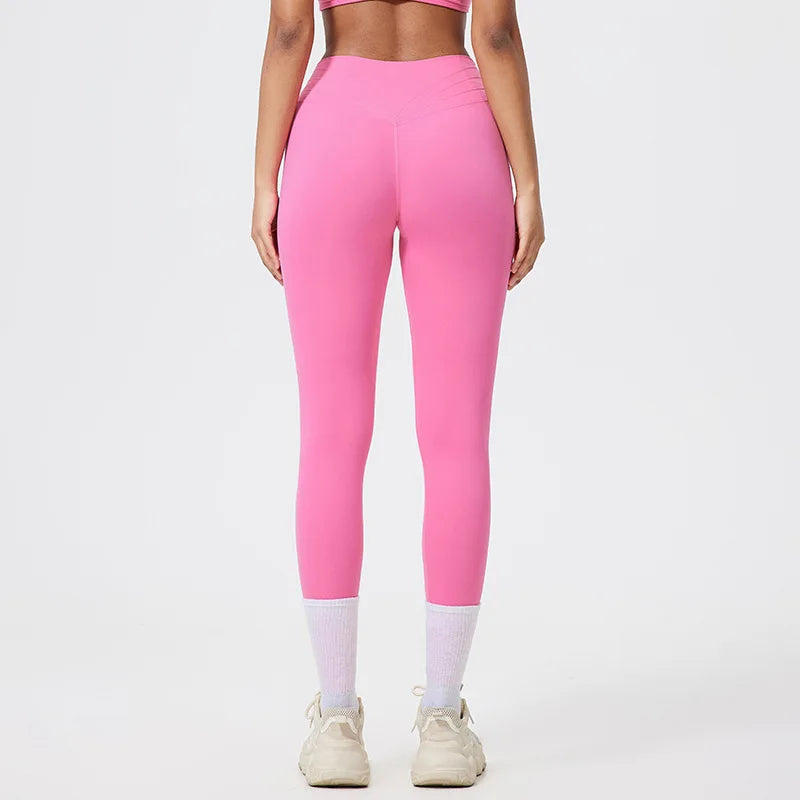 Model in bright pink seamless high-waist yoga leggings and white socks against a light background