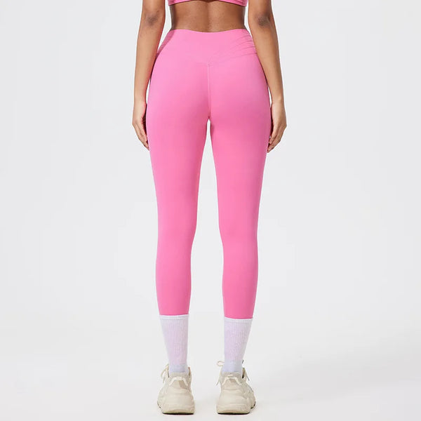 Model in bright pink seamless high-waist yoga leggings and white socks against a light background