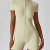 A model wearing a light beige seamless yoga jumpsuit with a mock neck collar.