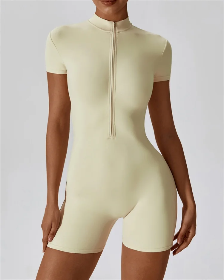 A model wearing a light beige seamless yoga jumpsuit with a mock neck collar.