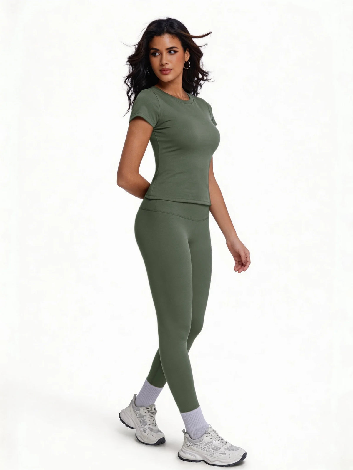 Una mujer modela un conjunto de yoga sin costuras de cintura alta en verde oliva con un top de manga corta y leggings.